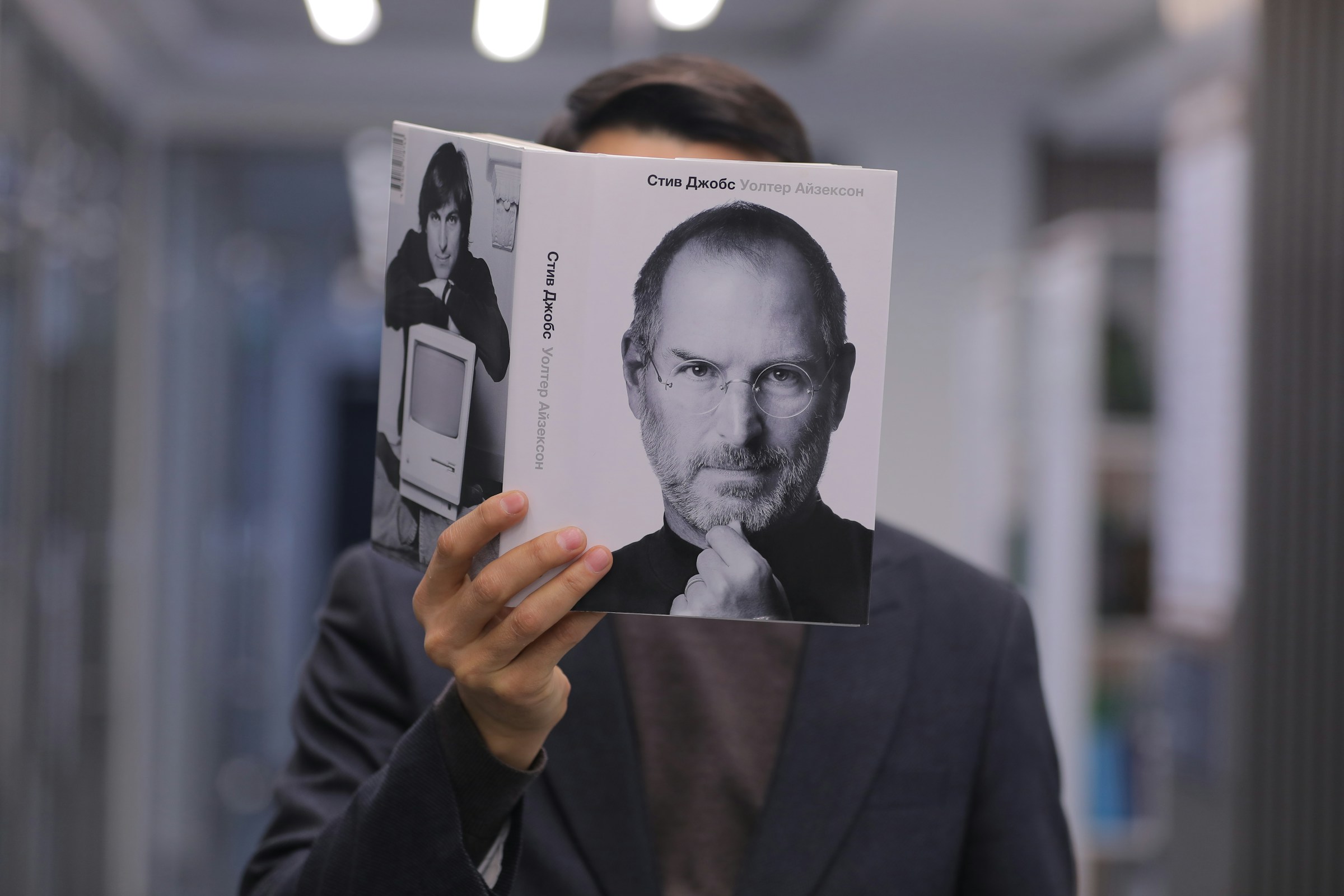 Man holding a book featuring Steve Jobs on the cover